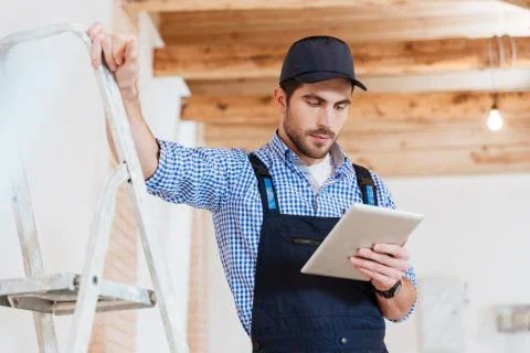 Builder using pc tablet computer in his work 写真素材