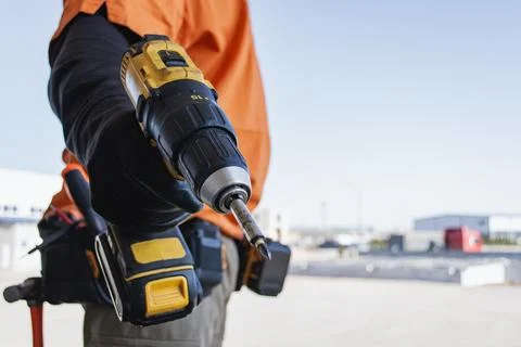 Builder using power tool on industrial site. Concept of professional manual l Stock Photos