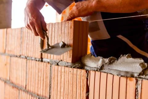 Builder using spatula to remove surplus mortar Stock Photos
