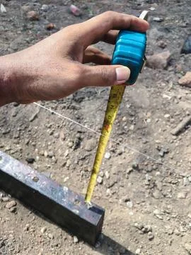 Builder is using a tape measure to find the distance between the ground and.. Stock-Fotos