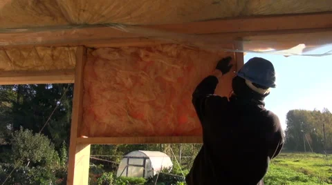 Builder wearing blue helmet insulating farm house frame Stock Footage 68714935