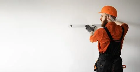 Builder wearing hardhat using spirit level measuring wall. repair, building.. Stock Photos