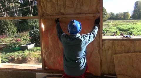 Builder wearing red pants insulating house wall 库存影片 68724328