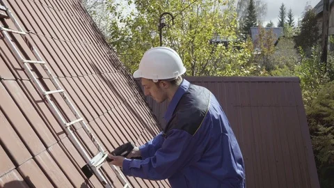 The builder in a white construction helmet and blue overalls mounts a ladder on Stock Footage 80242227