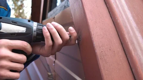 Builder in white helmet and blue robe repairs the roof of a country house with a Stock Footage 80243164
