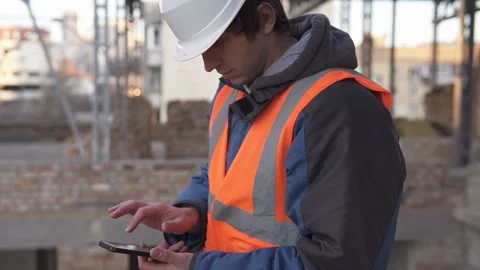 Builder in a white helmet with a smartphone at a construction site 库存影片 121503684