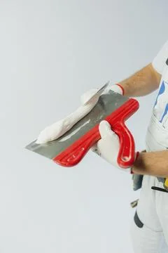 A builder in a white work uniform pours paint into a container, constructio.. Stock Photos