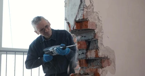 Builder work with building tool, break brick wall, plaster falls off, work dust Stock Footage 123951020
