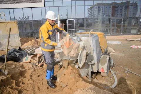 A builder in work clothes is doing his job, leveling the floor, pouring morta Foto stock