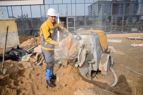 A builder in work clothes is doing his job, leveling the floor, pouring morta Stock Photos