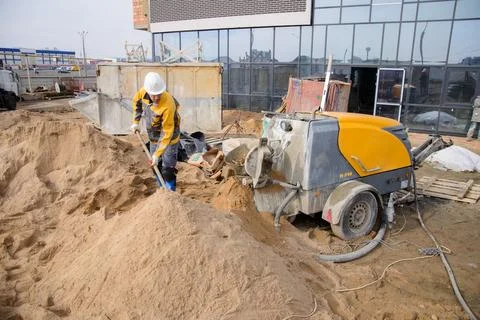 A builder in work clothes is doing his job, leveling the floor, pouring morta Stock Photos