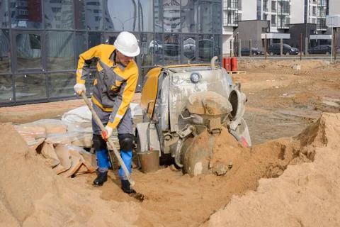 A builder in work clothes is doing his job, leveling the floor, pouring morta Stock Photos