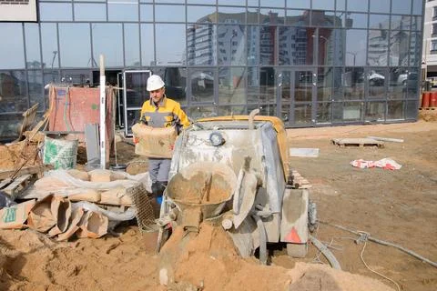 A builder in work clothes is doing his job, leveling the floor, pouring morta Stock Photos