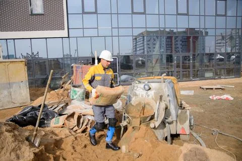 A builder in work clothes is doing his job, leveling the floor, pouring morta Stock Photos
