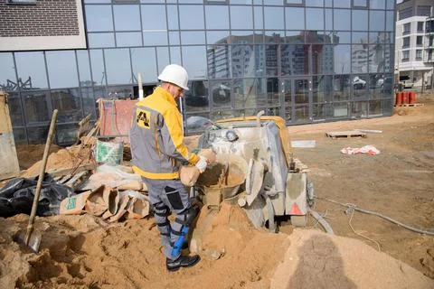 A builder in work clothes is doing his job, leveling the floor, pouring morta Stock Photos