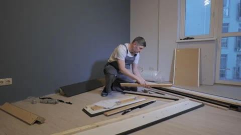 A builder in a work overalls is assembling a bed in a new apartment Stock Footage 170542294