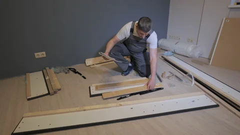 A builder in a work overalls is assembling a bed in a new apartment Stock Footage 171758298