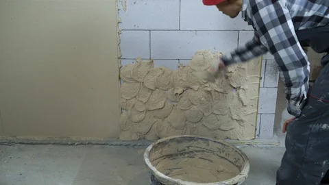 Builder in work wear putting plaster on aerated concrete block wall Stock Footage 102947958