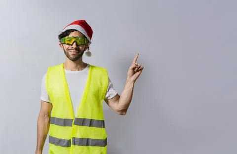 Builder worker with christmas hat pointing a finger at a promotion. Builder.. Stock Photos