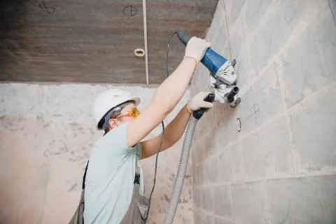 Builder worker cutting electrical chase in concrete wall with circulation saw Stock Photos