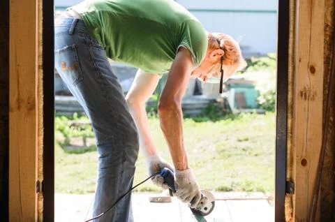 Builder worker with grinder machine cutting metal wood at construction site Foto stock