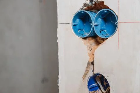 Builder worker installs plastic box under electrical outlet in hole wall Stock Photos