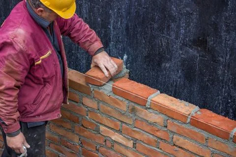 Builder worker laying solid clay brick Stock Photos