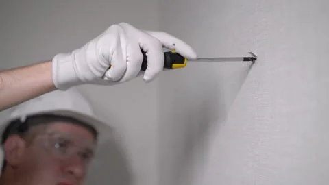 Builder worker makes repairs in apartment, screwing screw in a concrete wall. Vidéo 171125462