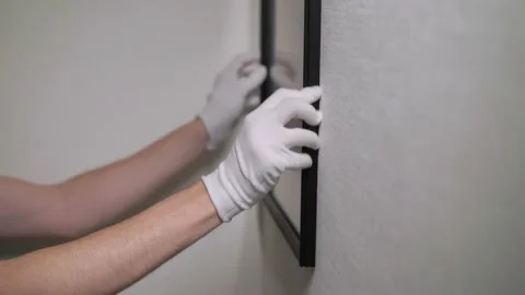 Builder worker makes repairs, hanging picture or photo in frame on wall. Stock Footage 175987264