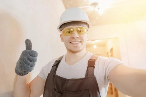 Builder worker man happy makes selfie photo with safety glasses and white helmet Stock Photos