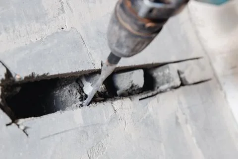 Builder worker man using jackhammer to drill into construction wall for duct for Stock Photos