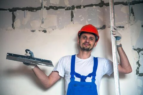 Builder worker plastering facade of high-rise building with putty knife Foto stock