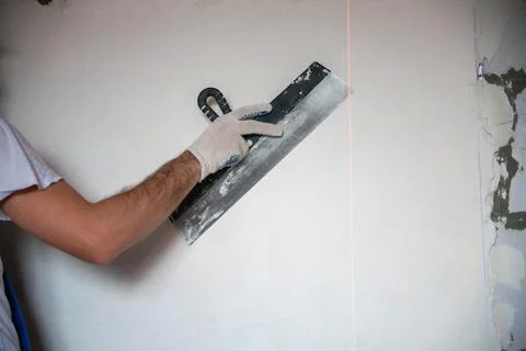 Builder worker plastering facade of high-rise building with putty knife Stock Photos