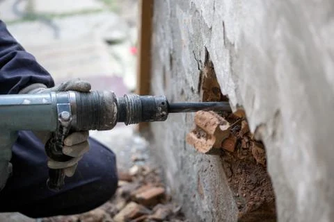 Builder worker with pneumatic hammer drill equipment breaking brick wall Stock Photos