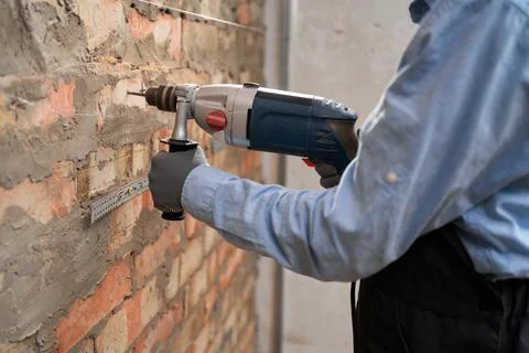 Builder worker with pneumatic hammer drill perforator making hole in wall wor Stock Photos