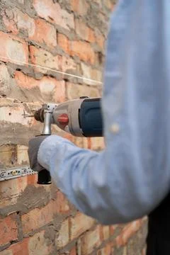 Builder worker with pneumatic hammer drill perforator making hole in wall wor Stock Photos