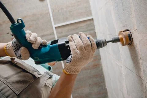 Builder worker pneumatic hammer drills hole in concrete brick wall with diamond Stock Photos