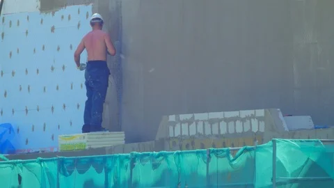 Builder working on facade thermal insulation and applying mortar over an Stock Footage 108432910