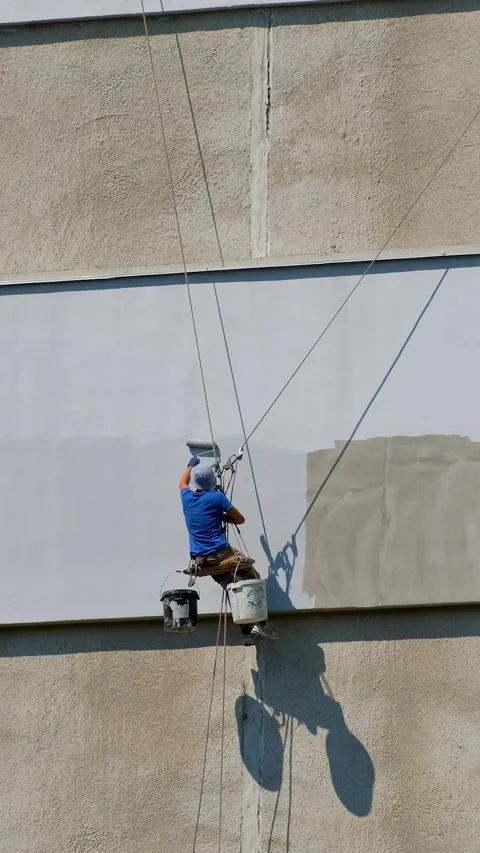 A builder is working at a height, holding on to a rope and safety net. The .. Stock Footage 306148890