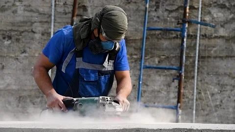 The builder works with an angle grinder Stockbeeldmateriaal 222586786