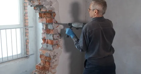 Builder works at construction site, destroys brick wall, demolition of partition Stock Footage 128788404