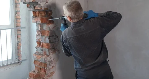 Builder works at construction site, destroys brick wall, breaks off pieces Stock Footage 128788540