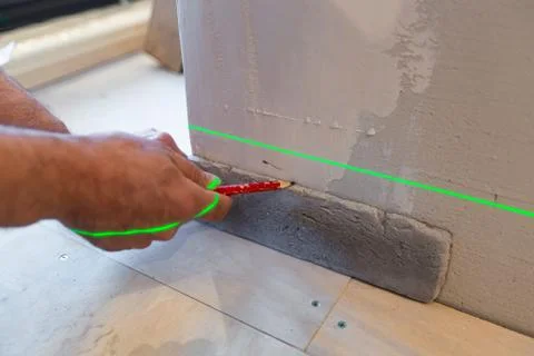 Builder works with a laser construction level in the apartment that is under Stock Photos