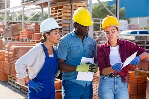 Builders and taskmaster having conversation in warehouse Stock Photos