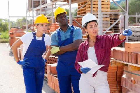 Builders and taskmaster having conversation in warehouse Stock Photos