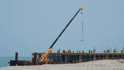 Builders and workers at construction site on sea pier on coastline Stock Footage 276644671