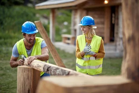 Builders are chatting while working on a wooden cottage in the forest. Cons.. Stock Photos