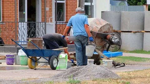 Builders are kneading a concrete solution with a concrete mixer. Video stock 112264892