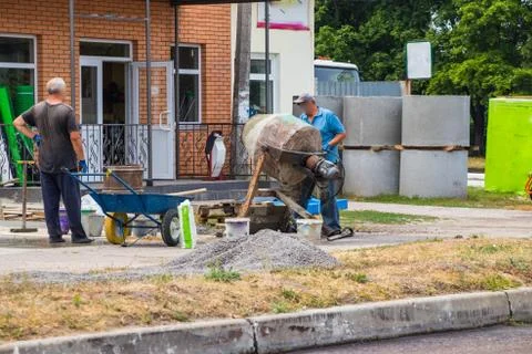 Builders are kneading a concrete solution with a concrete mixer. Stock Photos