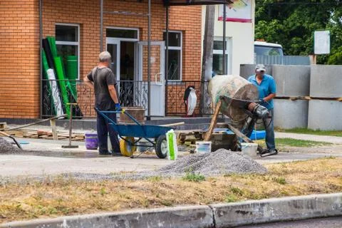 Builders are kneading a concrete solution with a concrete mixer. Stock Photos